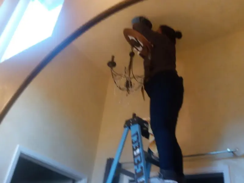 Electrician installing a chandelier in a Ross residence